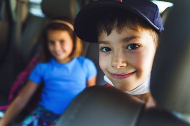 Yaz günü arabanın arka koltuğunda oturan küçük beyaz bir çocuğun portresini yakından çek - erkek ve kız kardeş küçük çocuklar seyahat ediyor - seçici bir odak noktası