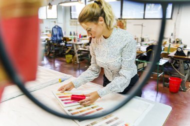 İşteki genç ve güzel yaratıcı kadın girişimci - Fabrikada ya da stüdyo tarafında yeni tasarım için paletten renk seçen güzel kadın - iş ve yaratıcılık kavramı