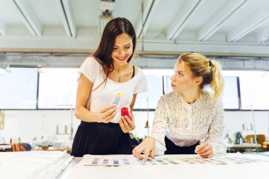 İki güzel kadın tasarımcı ellerinde renk paleti tutarak proje için malzeme seçiyorlar - iş yerinde bağımsız kadın girişimci - yaratıcılık ve ilham danışma konsepti