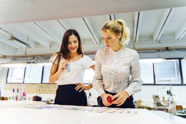 İki güzel kadın tasarımcı ellerinde renk paleti tutarak proje için malzeme seçiyorlar - iş yerinde bağımsız kadın girişimci - yaratıcılık ve ilham danışma konsepti