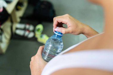 Spor salonunda elinde bir şişe su tutan ya da açan kimliği belirsiz beyaz bir kadın ya da kızın ellerine yakından bakın - Hidrasyon konsepti antrenmanında sportif kadın gündüz üst görünümü