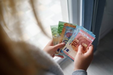 Avro banknotları maaş artışlarını sayarken ya da faturaları ödemeye hazırlanırken elinde bir yığın para tutan ve sayan Kafkasyalı kadının ellerini kapatın.