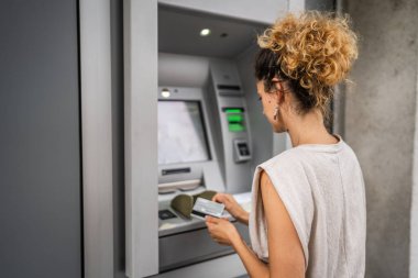 Kadın kredi kartı kullanıyor ve ATM 'den para çekiyor.