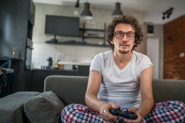 Yetişkin erkek, beyaz erkek, evde oyun konsolu video oyunu oynuyor. Oyun kumandası sizde. Keyfinize bakın ve kazanın ve başarı konseptini kopyalayın.