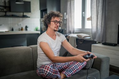 Yetişkin erkek, beyaz erkek, evde oyun konsolu video oyunu oynuyor. Oyun kumandası sizde. Keyfinize bakın ve kazanın ve başarı konseptini kopyalayın.