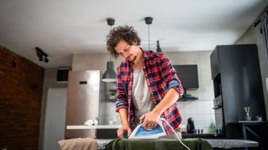 Evde ütü yapan bir adam, ev işlerinde gömleğini ütülüyor ev işlerinde ütü yapıyor 30 'lu yaşlarda evde tek başına yaşayan yetişkin bir erkek, fotokopi odasında çalışıyor.