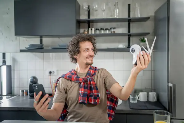 Caucasian man holding home security surveillance camera and mobile phone trying to install an app connecting setup and install cctv security video surveillance camera monitoring system