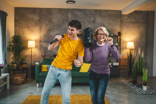 mother and son mature woman teenage man happy smile sing dance at home