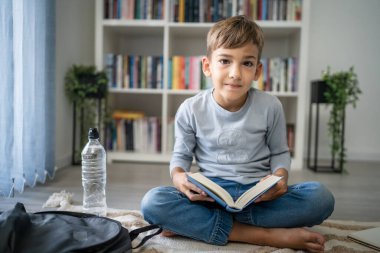 Beyaz tenli öğrenci evde ders kitabı okuyor. Okula hazırlanmayı öğrenin.