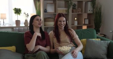 Kafkasyalı iki genç kız ya da erkek kardeş evde televizyon dizisi izleyip patlamış mısırla kanepede oturuyorlar.