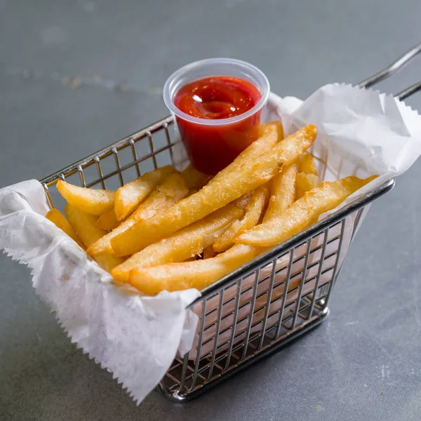 French fries in a steel basket on a table