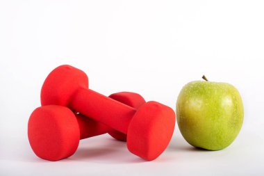 Kırmızı dumbbell ve yeşil elma Studio beyaz arka plan üzerinde izole. Diyet, fitness ve spor kavramı