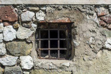 Eski Ortaçağ Kalesi hücre duvarı ile metal barlar, karanlık yaş penceresinde cezaevi