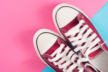 Kırmızı spor ayakkabılar çok renkli pastel yüzeyinde yalan. Üstten görünüm. Retro moda. Yakın çekim
