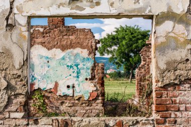 Hasarlı duvar ve pencere çerçeve Harabeleri Oda ve yeşil alan çimen, ağaç ve mavi bulutlu gökyüzü manzaralı. Kırmızı tuğla duvar çatlaklar