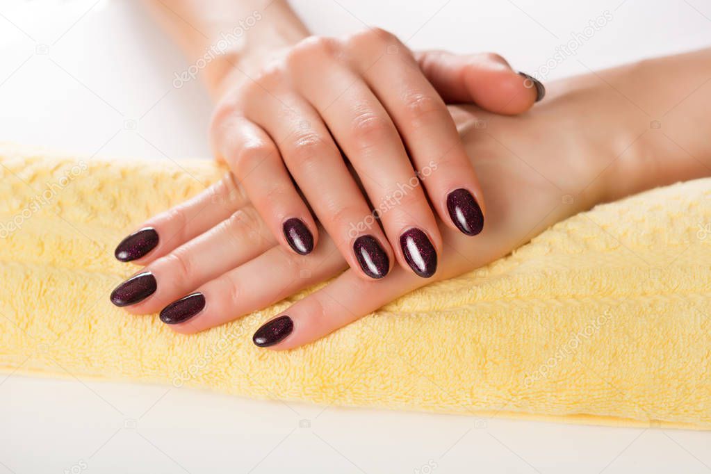 Purple nail art with tinsels on yellow towel. Manicure and Beauty concept. Close up, selective focus