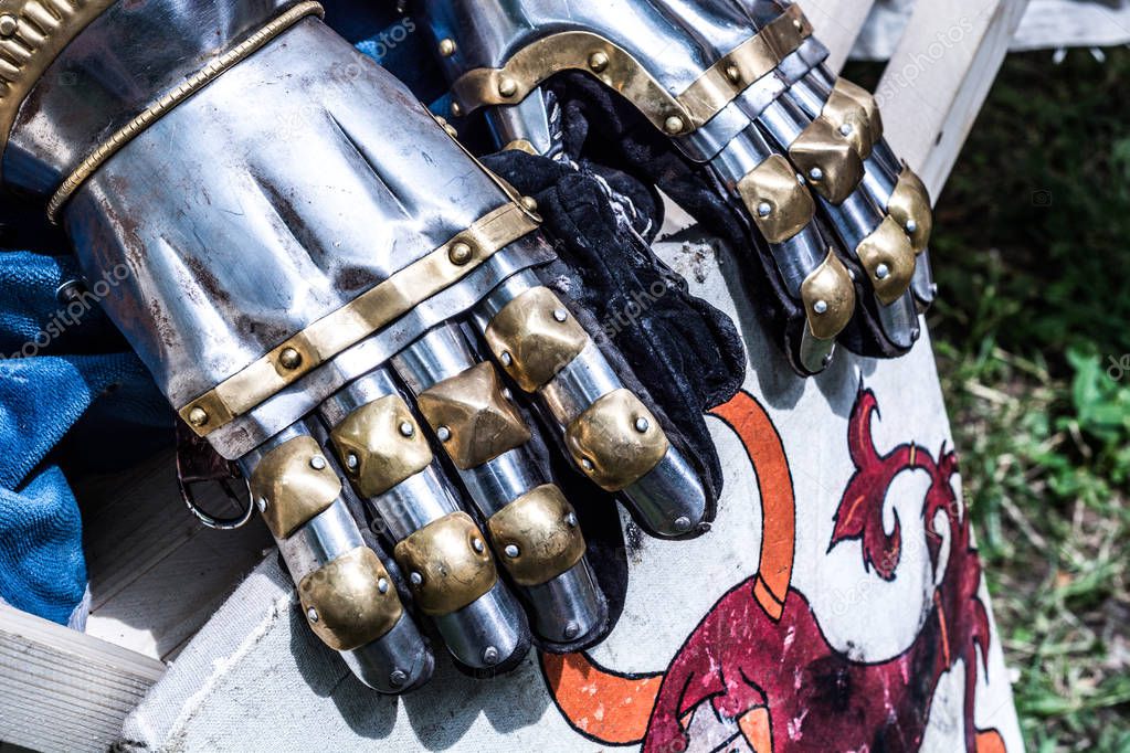 Medieval knight metal hand gloves on shield. Traditional knights weapons at middle age theme festival. Close up, selective focus