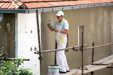 Nis, Sırbistan - 16 Haziran 2018: Cephe sıvacı beyaz üniforma ile iskele üzerinde var. Alt yalıtım cephe eve yenileyen
