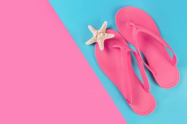 Pembe sandalet flip flop ve denizyıldızı mavi ve pembe pastel arka plan üzerinde. Boş tarafı metin ve kopya alanı için. Yaz tatil kavramı. Üstten görünüm