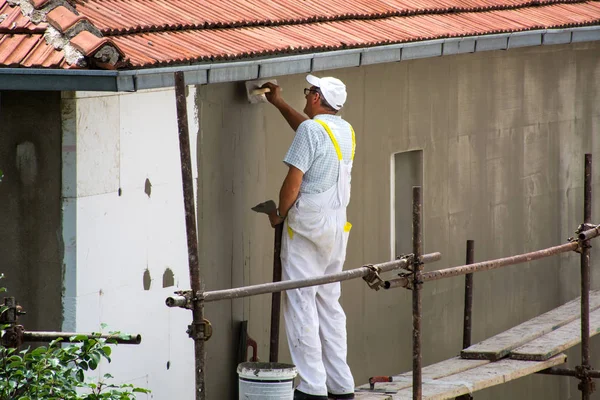 Niş, Sırbistan - 16 Haziran 2018: işçisi mala ev cephesinde köpük yalıtım ve kafes harç yaymak. İskele üzerinde Beyaz üniformalı adam