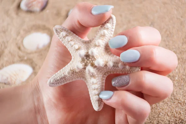 Menina Com Unhas Manicure Azul Polonês Segurando Estrela Mar Mão — Fotografia de Stock