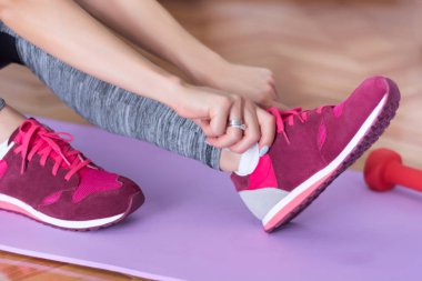 Kız el Kırmızı spor ayakkabılar iş dışarı için evde yoga ya da fitness mor mat parke üzerinde hazırlanıyor. Spor ve rekreasyon kavramı. Yakın, seçici odak