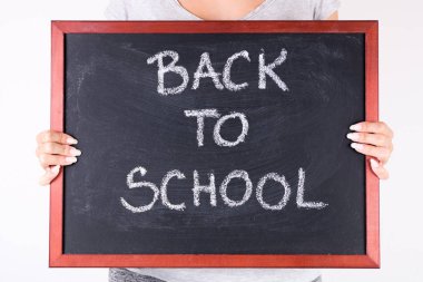 Büyük yazı tahtası okula tebeşir metinle elinde tutan genç kız. Eğitim kavramı. Yakın, seçici odak