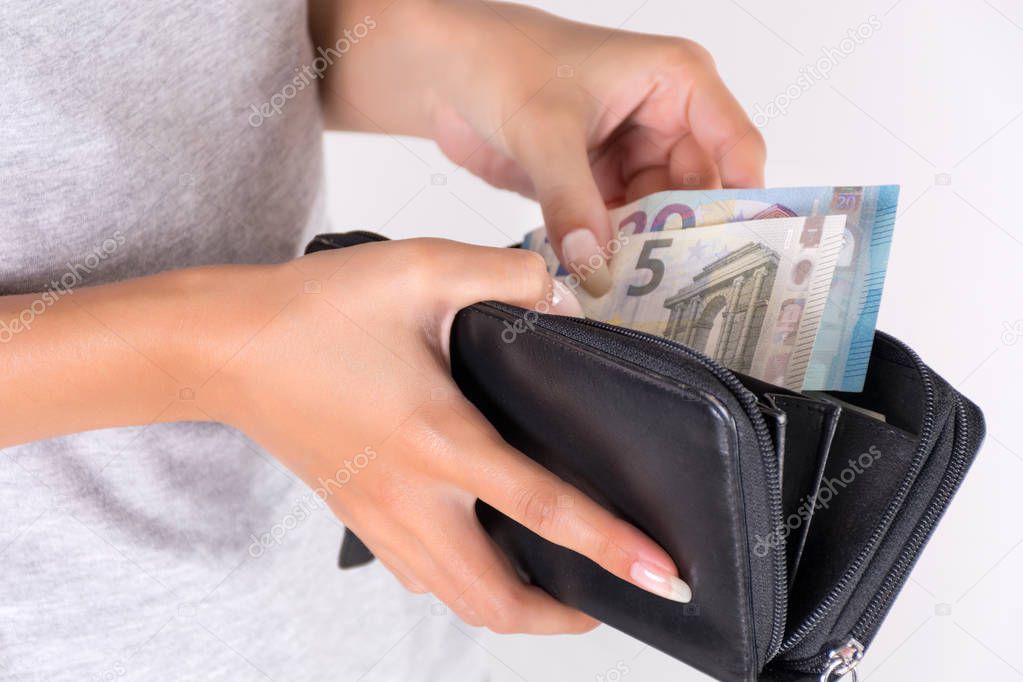 Young female hands holding black wallet with Euro money and pay. Economy and shopping concept. Close up, selective focus