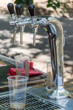 Krom bira musluk ve plastik cam caz müzik festivali Park'ta boş. Alkol içki kavramı. Yakın, seçici odak