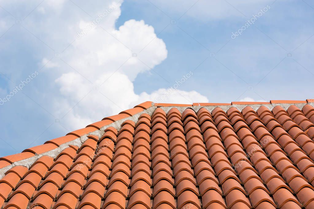 Orange roof tile pattern over blue and cloudy sky. Roof on modern house building. Close up
