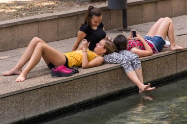 Niska Banja, Sırbistan - 16 Ağustos 2018 kızlar spa resort ve bacakları su rahatlatıcı ve seyir içinde akıllı telefon suya yakın yalan söyler. Dinlenme ve yaz tatil kavramı. Yakın, seçici odak