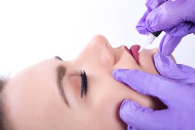 Güzellik uzmanı kalıcı uygulama üzerinde kırmızı dudaklar makyaj. Güzel genç kız dudaklarında kırmızı pigment dövme. Yakın, seçici odak