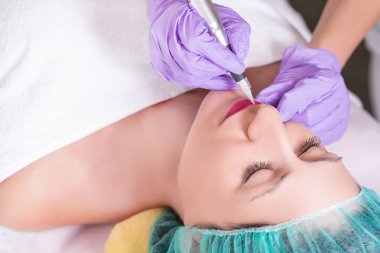 Kalıcı olması güzel genç kadın makyaj profesyonel güzellik Studio dudaklarında. Kız koruyucu kapak ve havlu ile yatakta yatıyor. Yakın, seçici odak