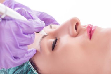 Kalıcı makyaj güzellik stüdyosu genç kadındaki kaşları üzerinde uygulanması. Profesyonel aracı ile dövme güzellik uzmanı. Yakın, seçici odak