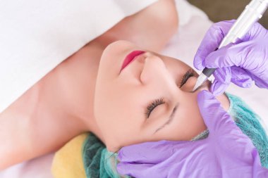 Kaşları genç kadın üzerinde kalıcı uygulama güzellik uzmanı telafi etmek. Kız yalan güzellik Studio koruyucu kapak ve havlu ile yatakta. Yakın, seçici odak