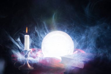 Sihirli kristal ışık topu mum Şamdan ve Kitaplar ile masada, topu sigara ve siyah arka plan üzerine. Cadılar Bayramı kavramı. Yakın, seçici odak