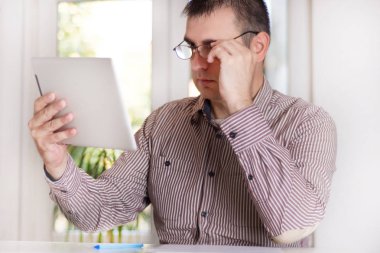 Modern ofis ve holding ve dijital tablet gözlük ile bakarak otururken yakışıklı bir genç işadamı portresi. Adam çalışma kavramı ofis. Yakın, seçici odak