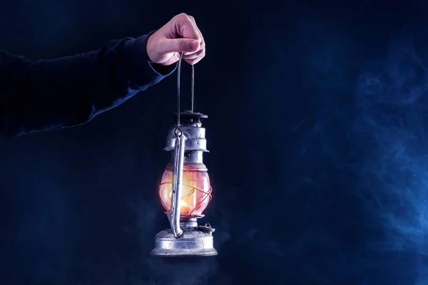 Karanlık ve gece gaz fener tutan adam el sisli arka plan füme. Gaz veya petrol lamba yakma. Korku ve Cadılar Bayramı kavramı. Yakın, seçici odak