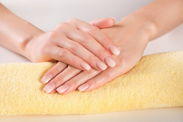 Ombre manicure on woman gently hands on yellow towel in beauty studio. Manicure concept image. Close up, selective focus