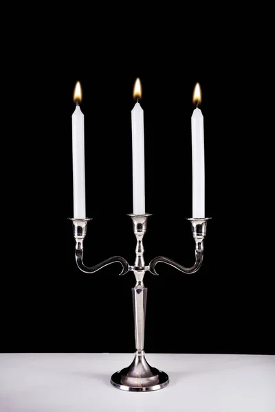 银色巴洛克烛台与三白色石蜡蜡烛燃烧在办公桌和黑色背景 浪漫和时尚的概念 — 图库照片
