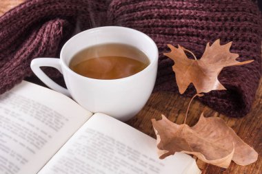 Sonbahar konsepti görüntüsüyle fincan çay ve açık kitap ve düşmüş kuru yaprak. Sezon retro ve vintage kavramı. Yakın, seçici odak