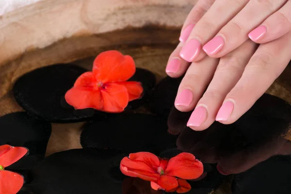 ピンクのマニキュアで女性指の爪ポーランド語ゲル赤い花と黒い石の木製のボウルの水の上 間近で 選択と集中 — ストック写真