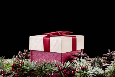 Hediye kutusu ile kırmızı yay ve köknar ağacı çam koni, siyah arka plan ile. Noel ve yeni yıl tatil kavramı. Yakın, seçici odak