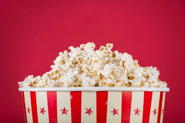 Popcorn in retro box isolated on red background. Movie and cinema food concept. Close up, selective focus