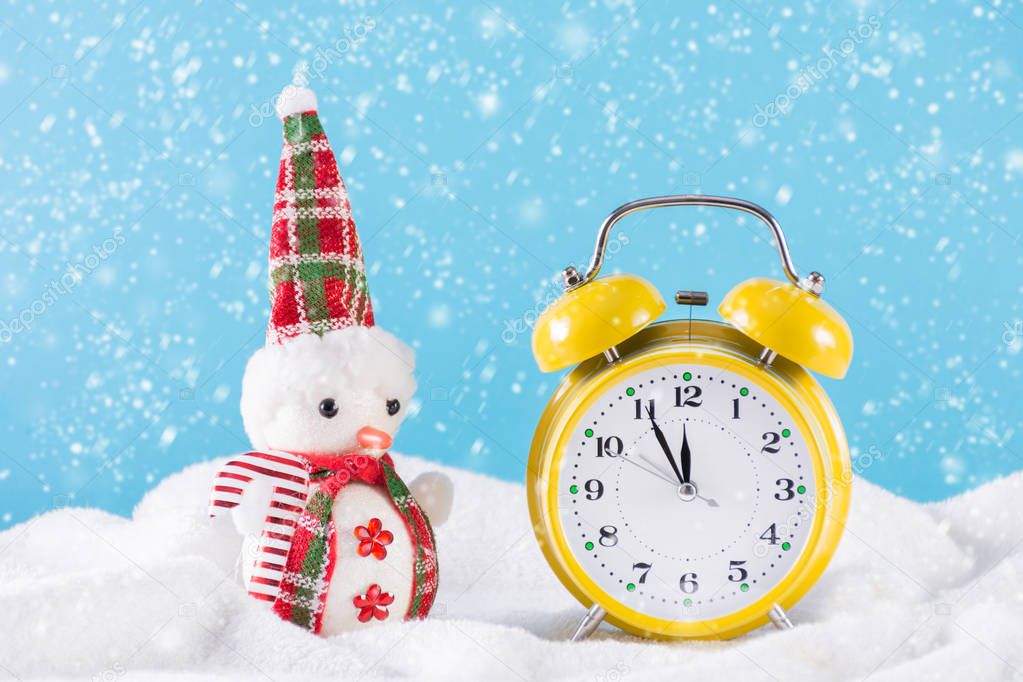 Snow man and retro clock on snow and it's snowing at winter day. Blue background and snowflakes falling. Christmas and New Year time concept