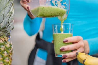 Kız onun favori yeşil smoothie blender evde mutfak cam üzerinden dökülen. Sağlıklı ve detoks yiyecek ve içecek konsepti. Yakın, seçici odak