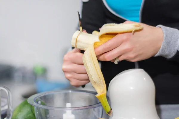Girl hands cuts and preparing banana for smoothie. Make detox shake healthy drink. Close up, selective focus