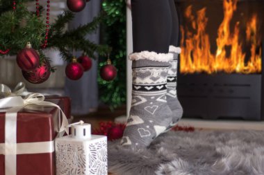 Kız ayak parmakları Noel yuva ayakta ve şömine yakın süslenen Xmas ağacı. Noel ve yeni yıl kavramı. Yakın, seçici odak