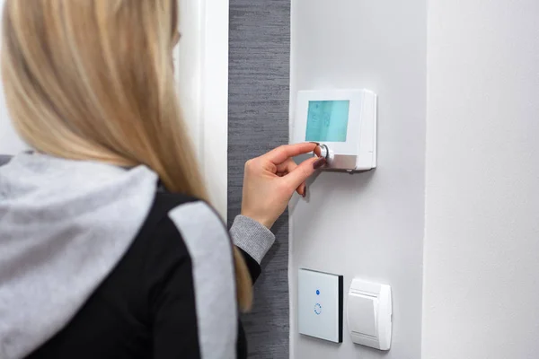 Kız ayarlar ve oda sıcaklığında duvarda akıllı anahtar üzerindeki düzenler. WiFi ışık anahtarı ve Sıcaklık regülatörü akıllı. Akıllı ev kavramı. Yakın, seçici odak