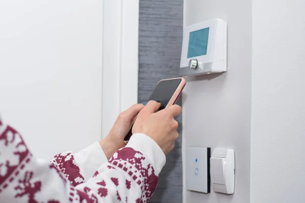 Kız ayarlar ve akıllı telefon anahtarı Duvar ile Oda sıcaklığında düzenler. WiFi ışık anahtarı ve Sıcaklık regülatörü akıllı. Akıllı ev kavramı. Yakın, seçici odak